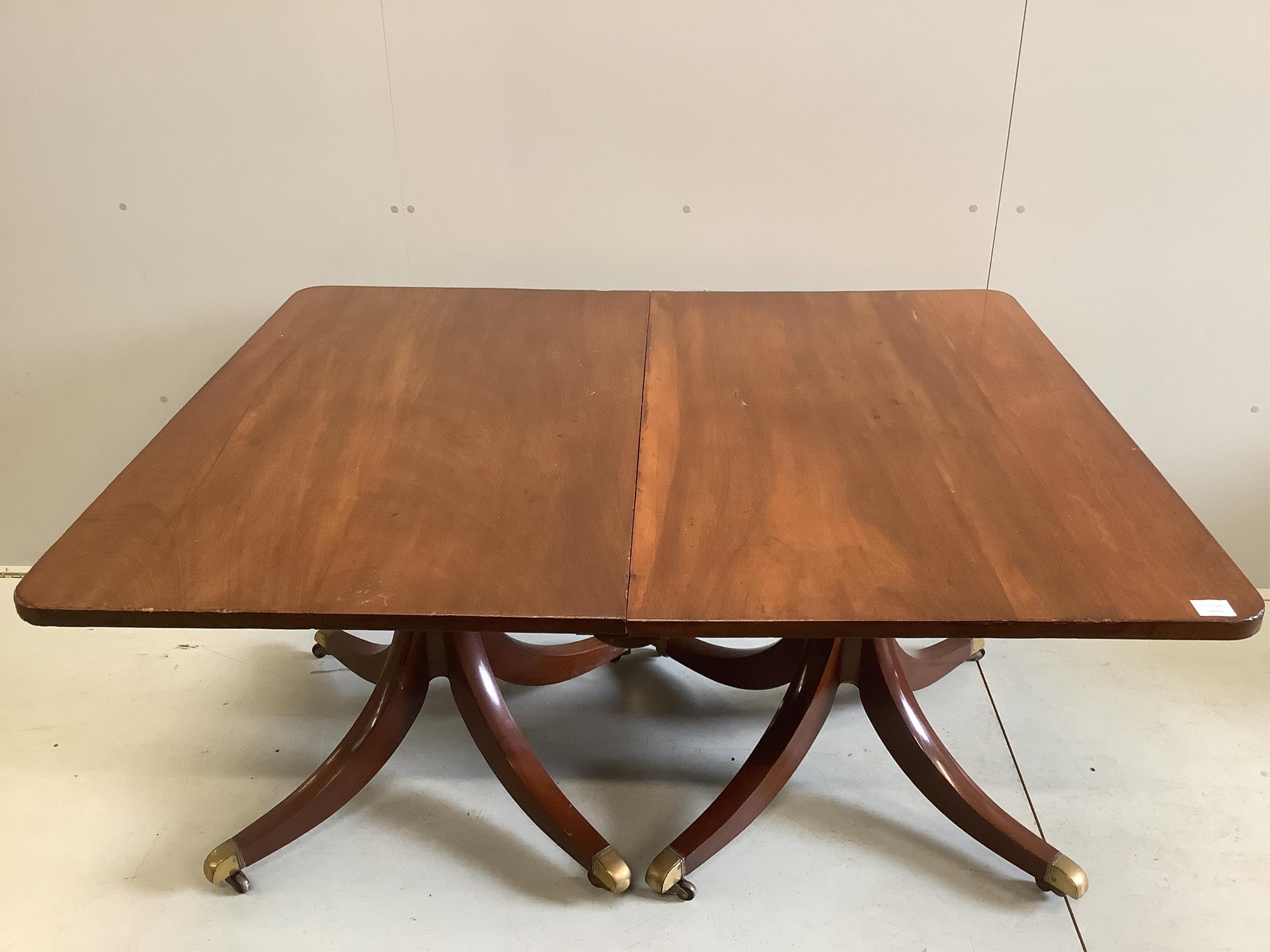 A Regency mahogany twin pillar extending dining table, width approximately 240cm extended, two spare leaves, depth 120cm, height 72cm. Condition - fair